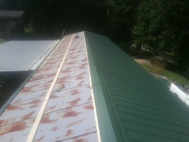 Old rusted panels beside newly installed green metal roofing — Wind Damage Roof Repair by Roofing Brothers in Moodus