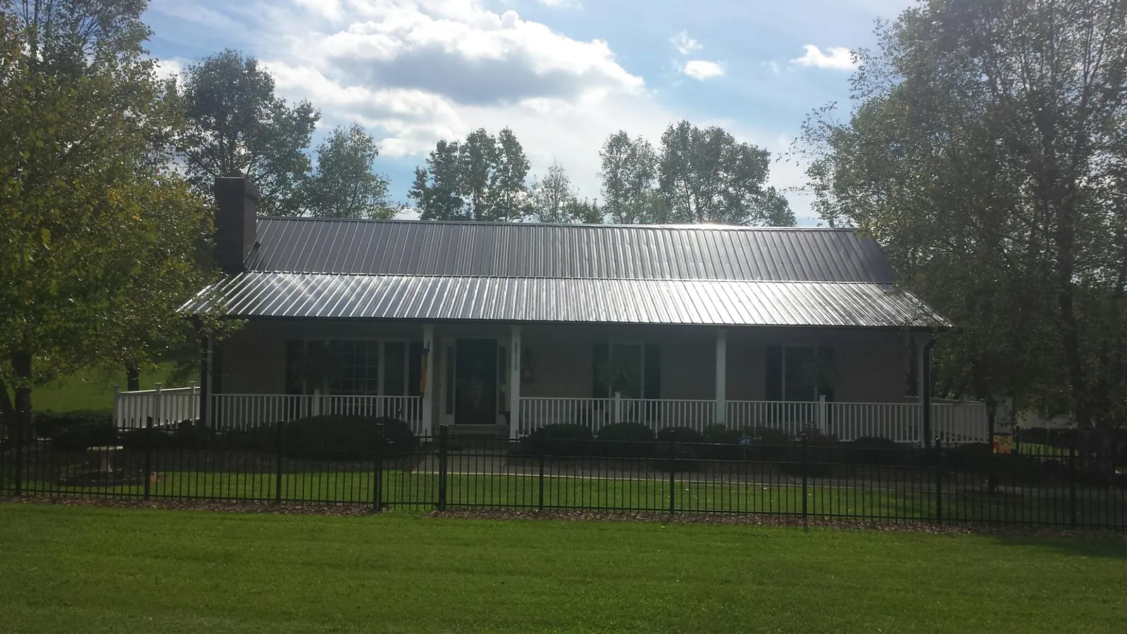 Gray metal roof on a brick ranch with a full width front porch — Gutter Guard Installation work by our crew in Moodus